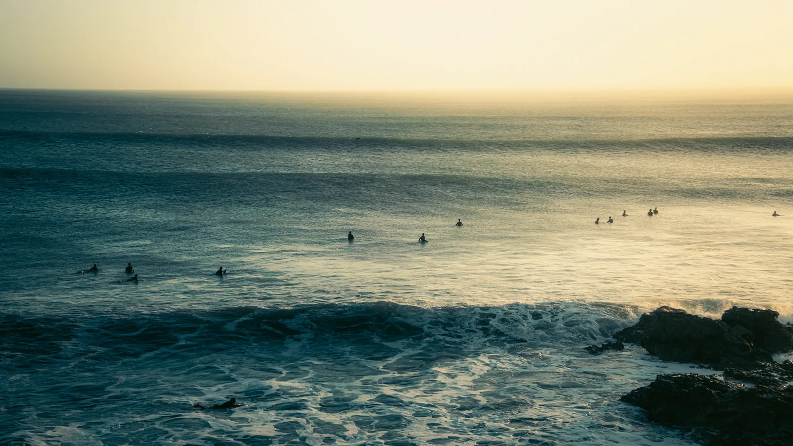 Surfers scattered across a golden lineup waiting for a set off the coast of Essaouira, Morocco