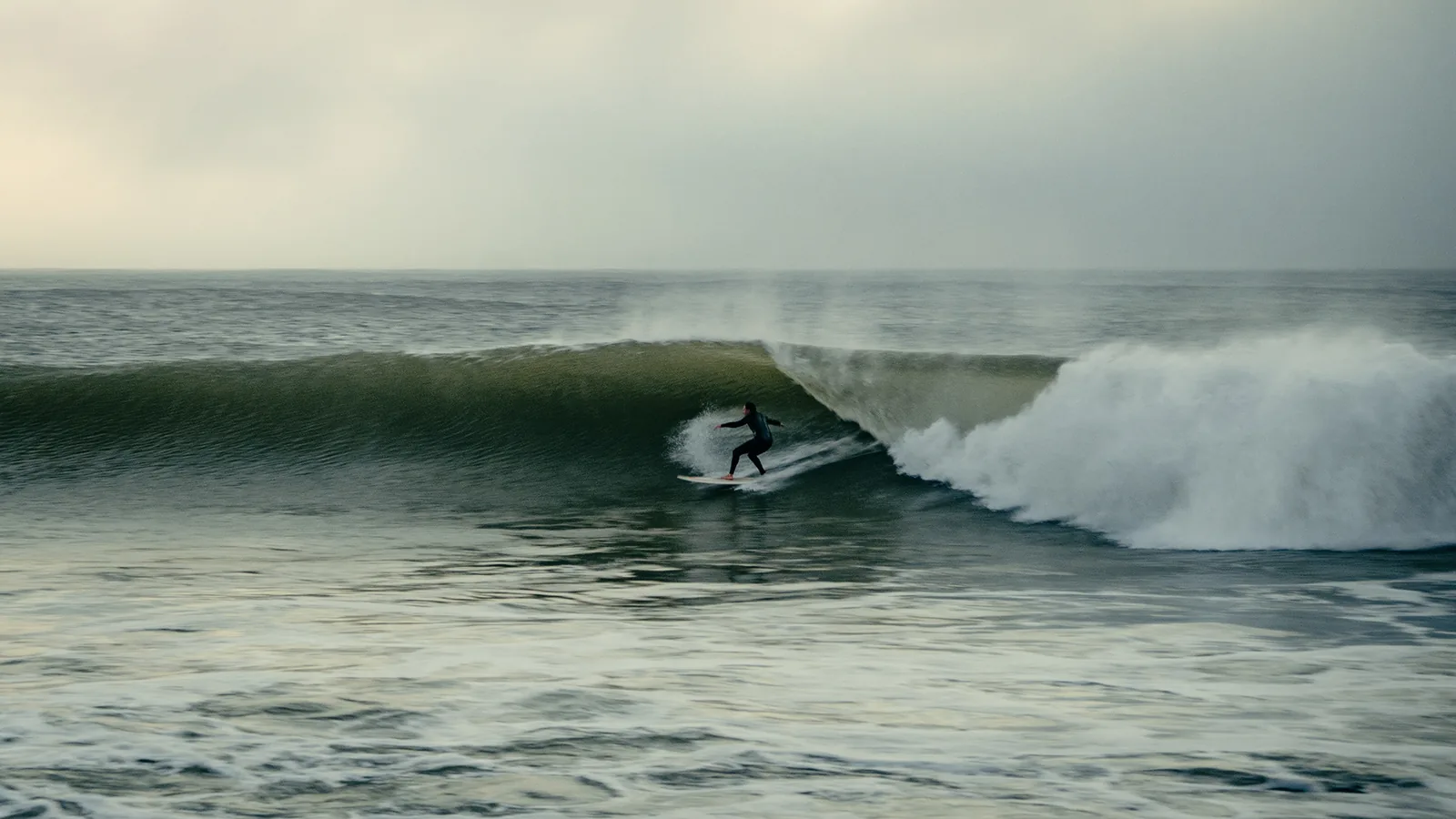 Surfer carving a smooth bottom turn on a clean green wave off Essaouira, Morocco