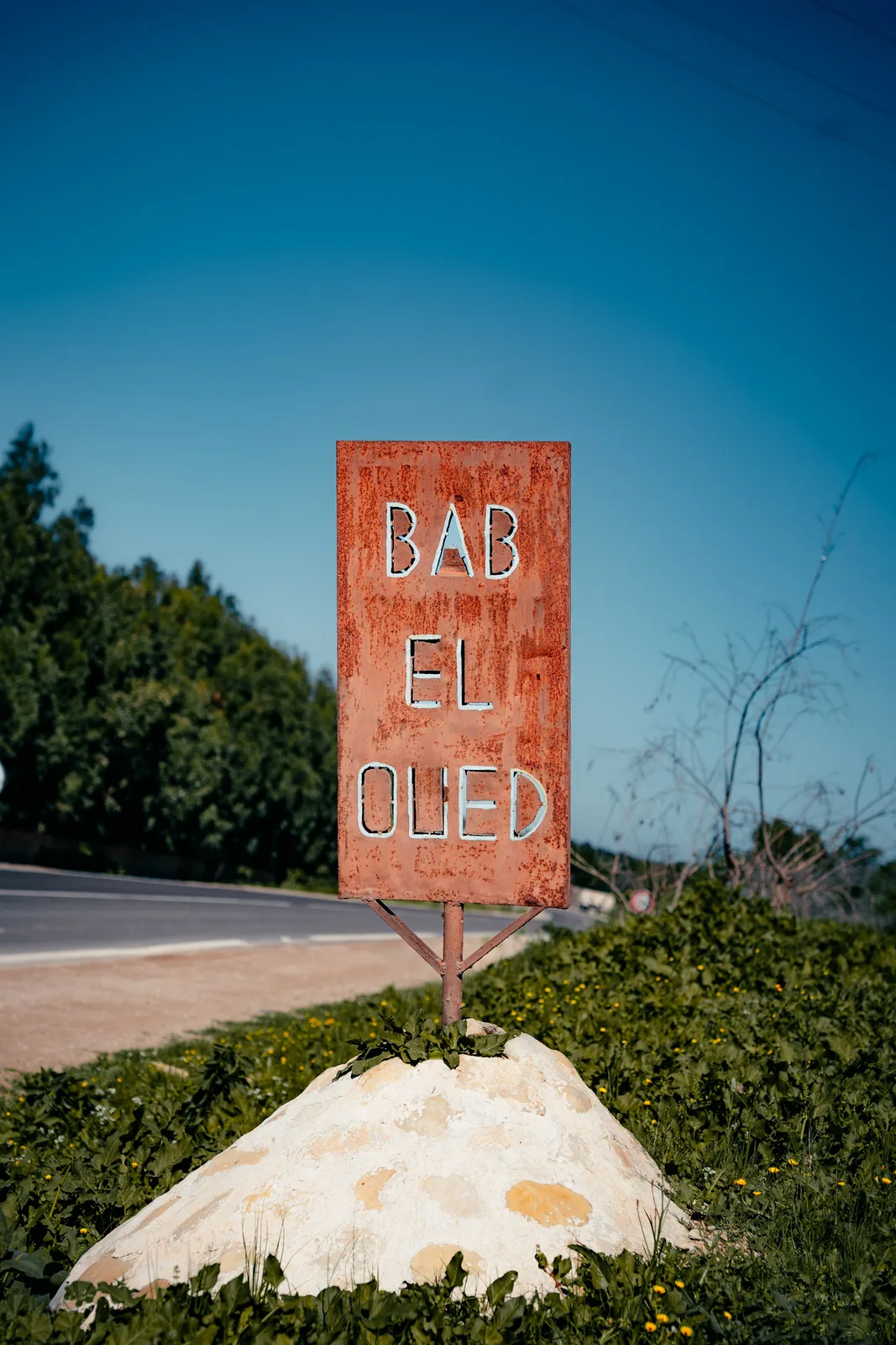 Weathered roadside sign reading Bab el Oued standing beneath a clear sky near Essaouira, Morocco