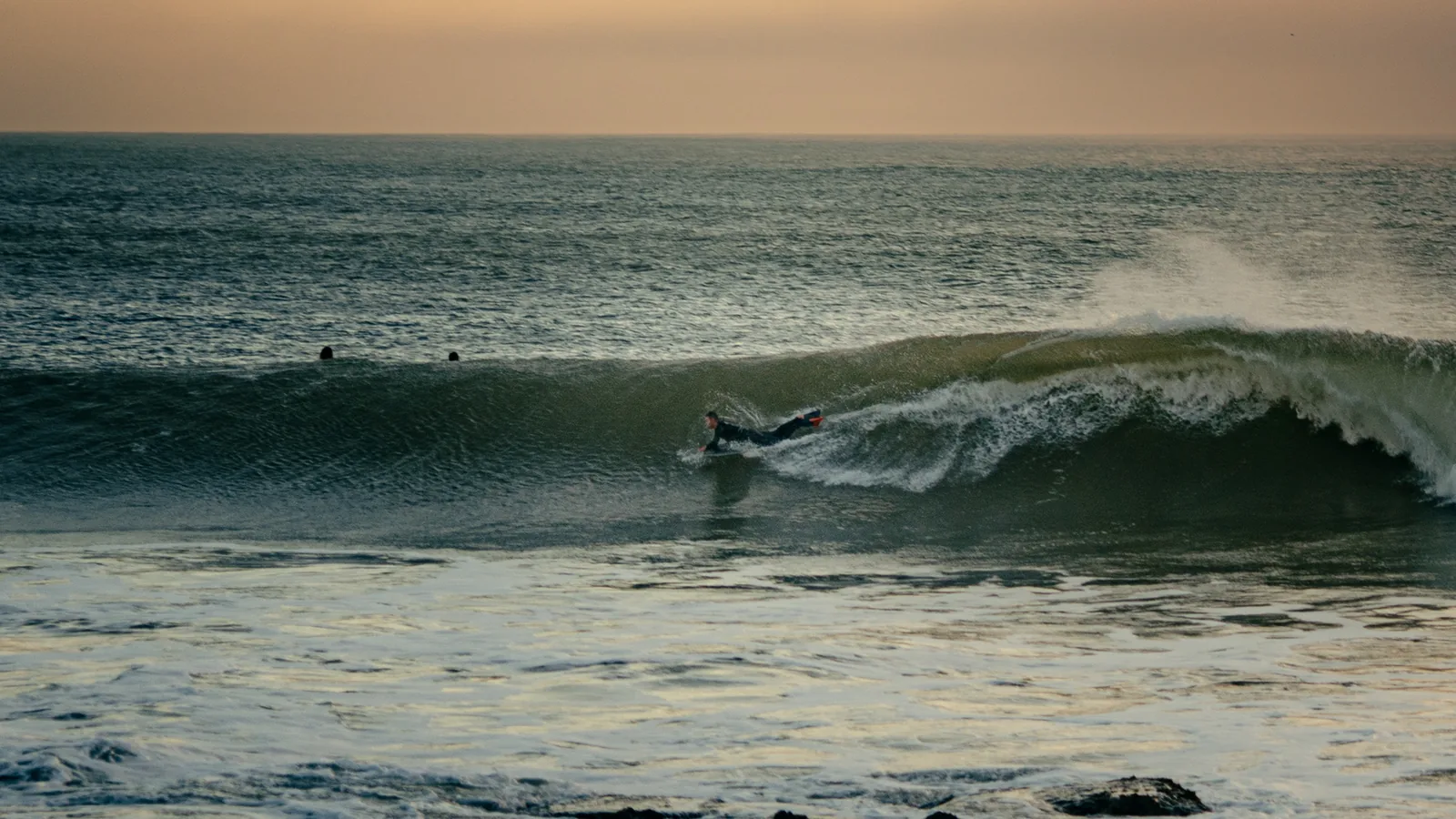Surfer streaking across a wave face while others wait for the next set off Essaouira, Morocco