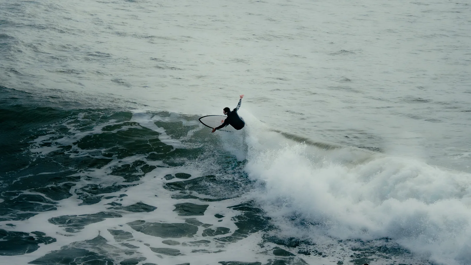Surfer whipping a sharp cutback and throwing spray off a wave in Essaouira, Morocco