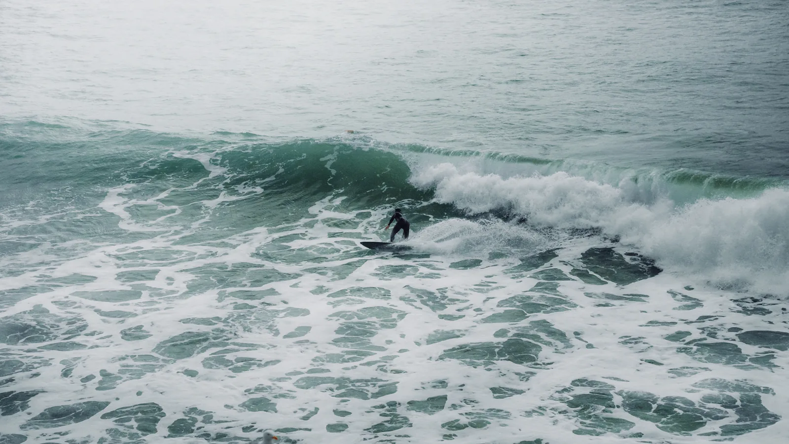 Surfer trimming along a breaking wave through churning whitewater off Essaouira, Morocco