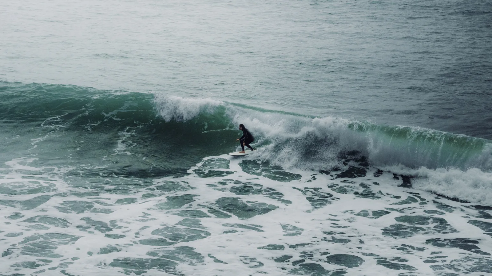 Surfer carving a turn on a translucent green wave face in Essaouira, Morocco