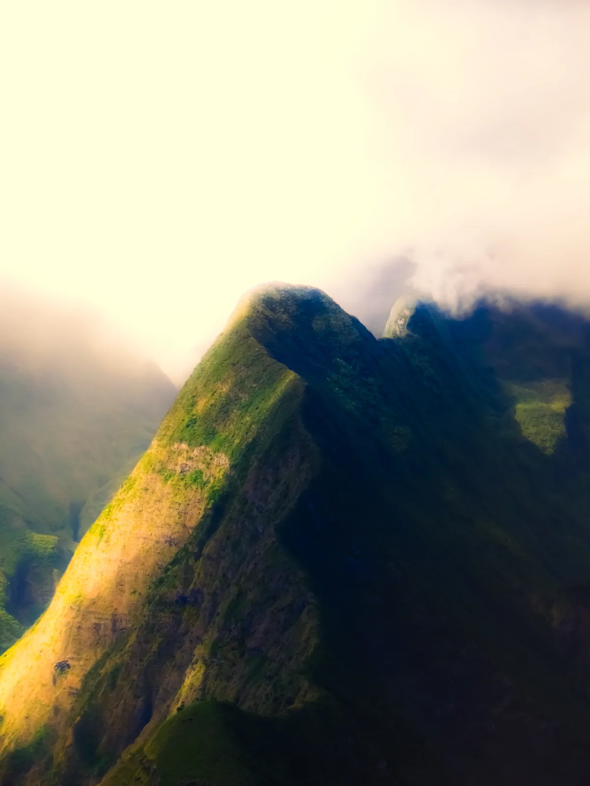Sunlit ridge peak breaking through morning mist on Reunion Island, France