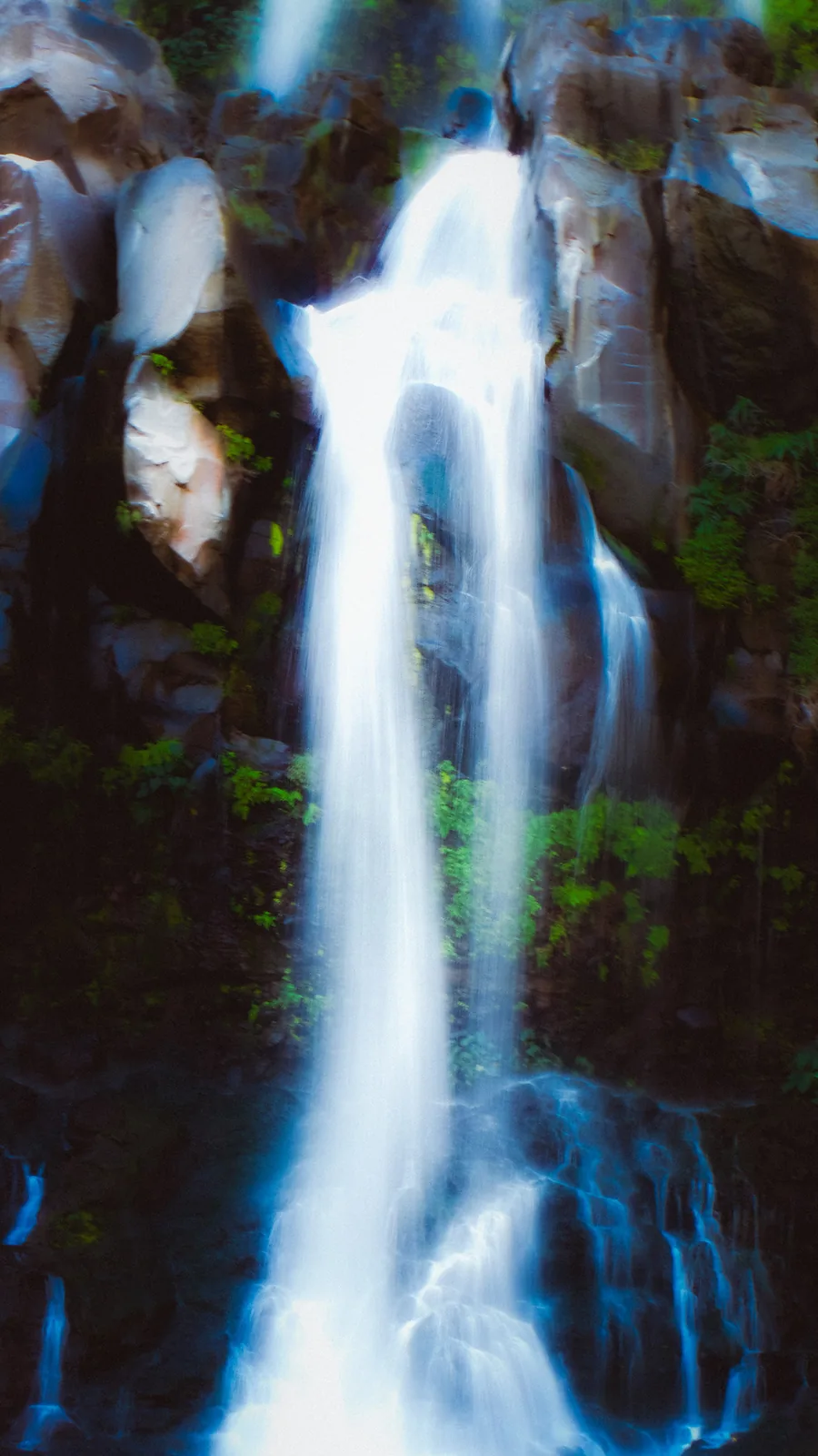 Twin streams of a waterfall tumbling over dark volcanic rock on Reunion Island