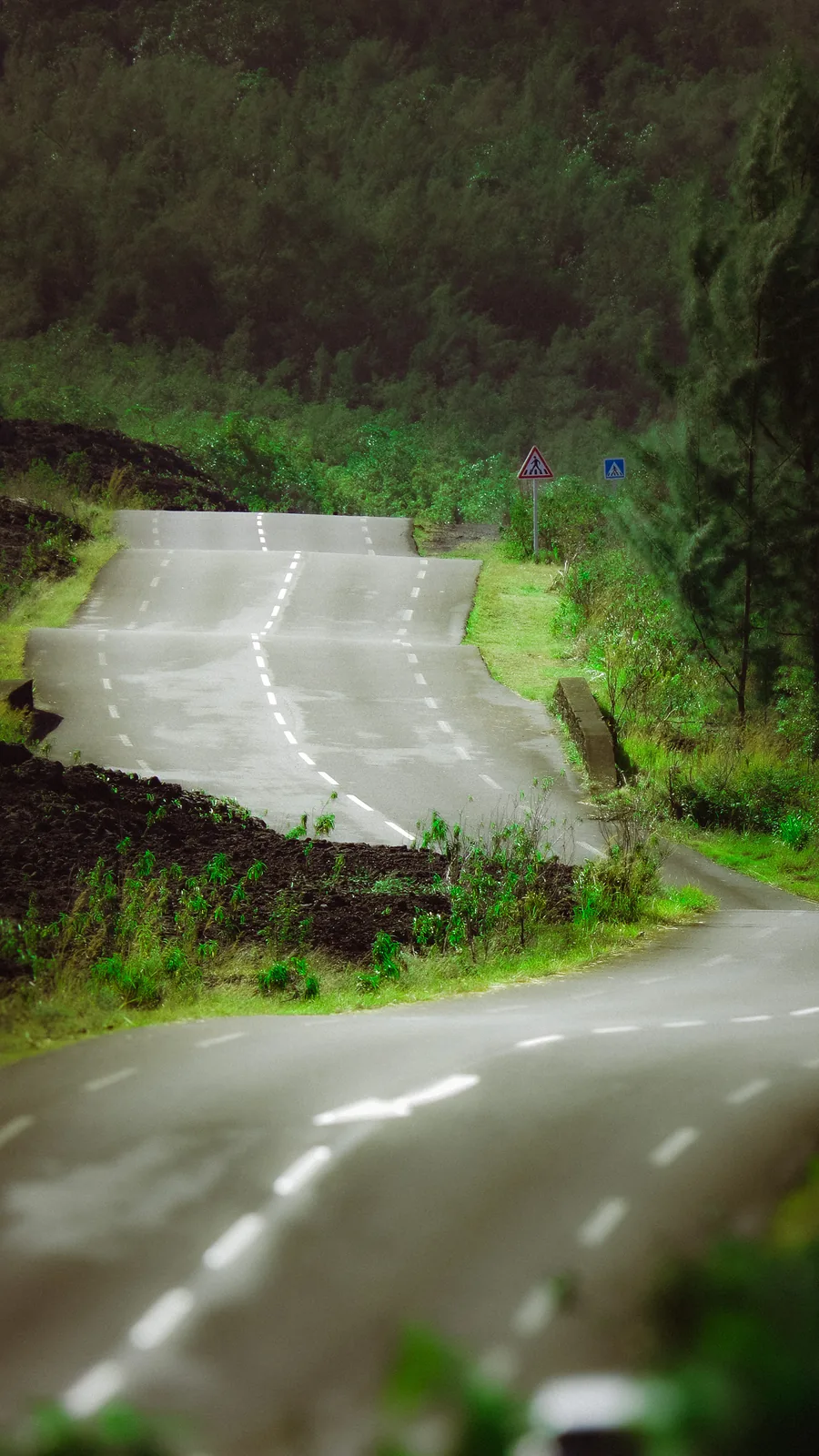 Empty mountain road winding past low cloud and greenery on Reunion Island