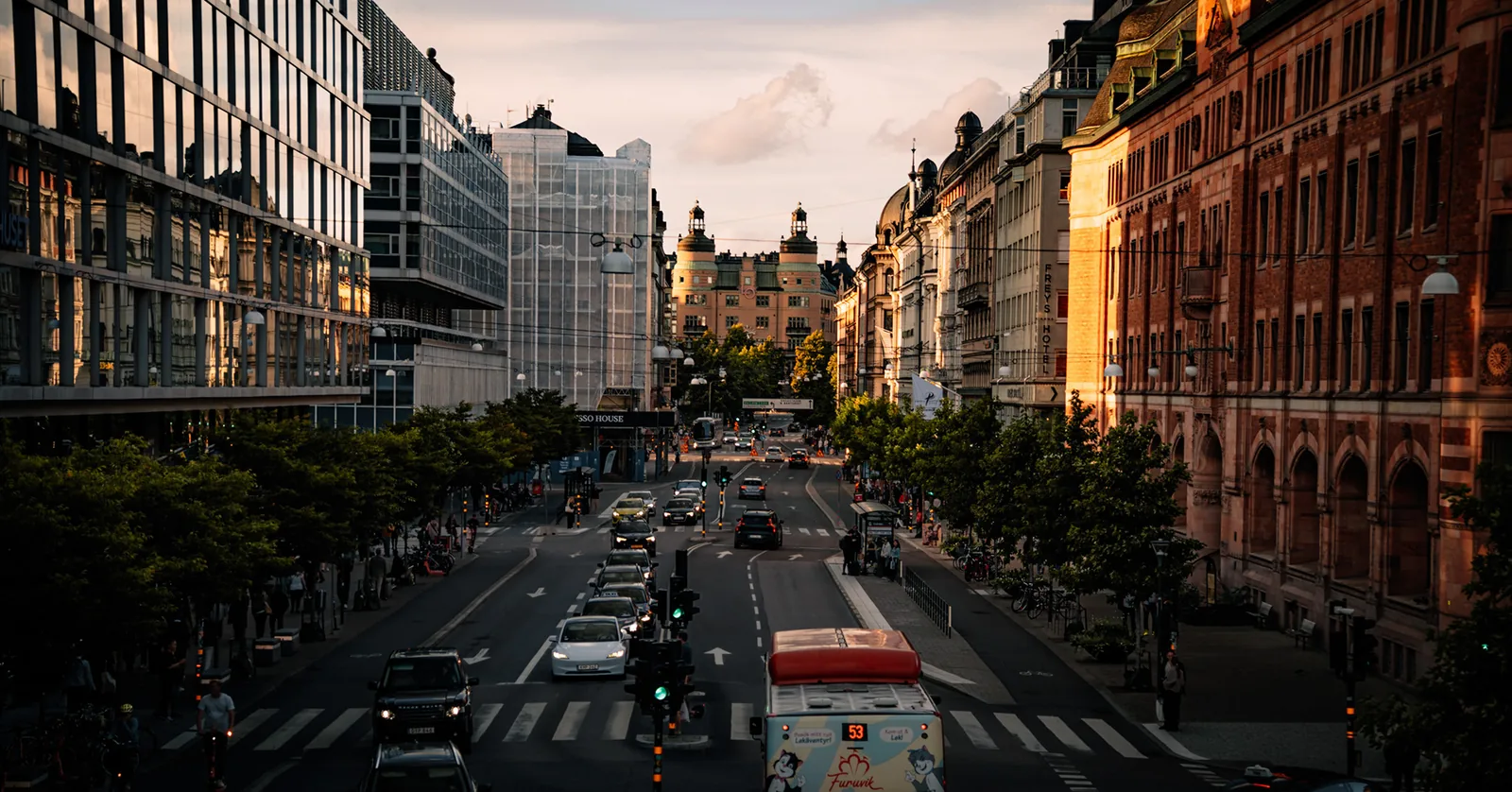 Busy city avenue lined with historic buildings glowing in evening light in Sweden