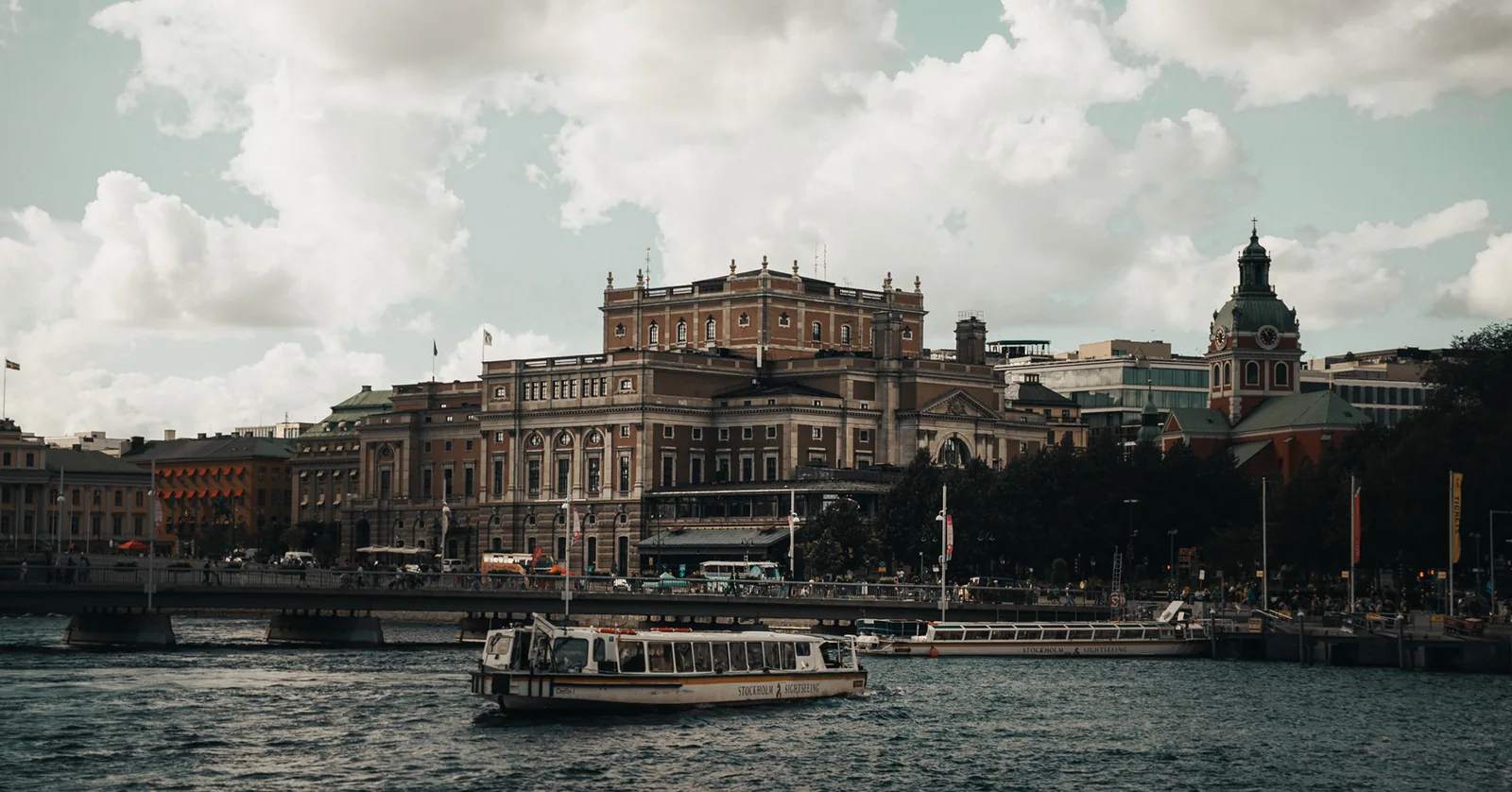 Passenger ferry crossing the harbor in front of a grand waterfront building in Sweden