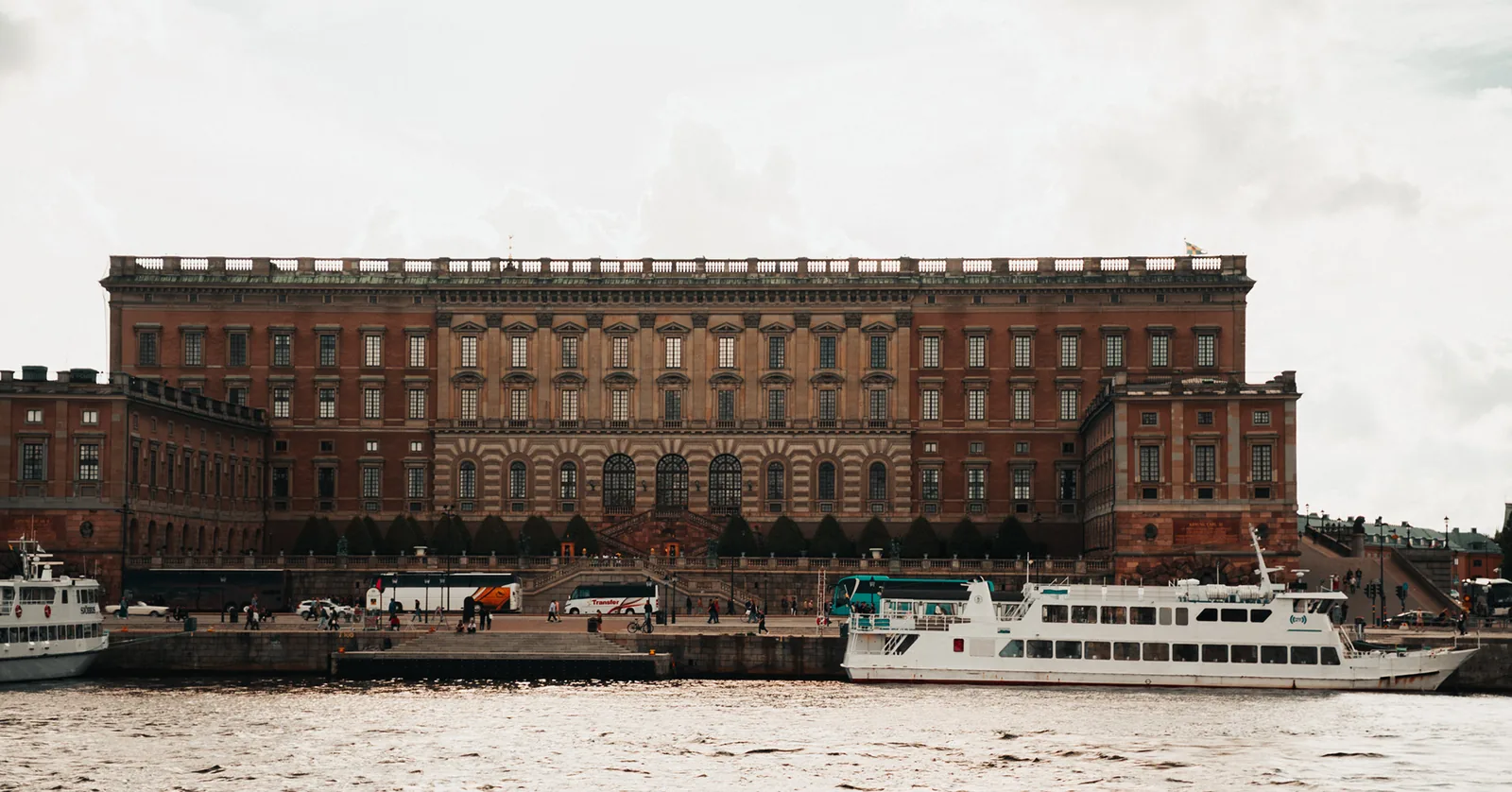 Boats docked before a monumental red-brick palace on the waterfront in Sweden