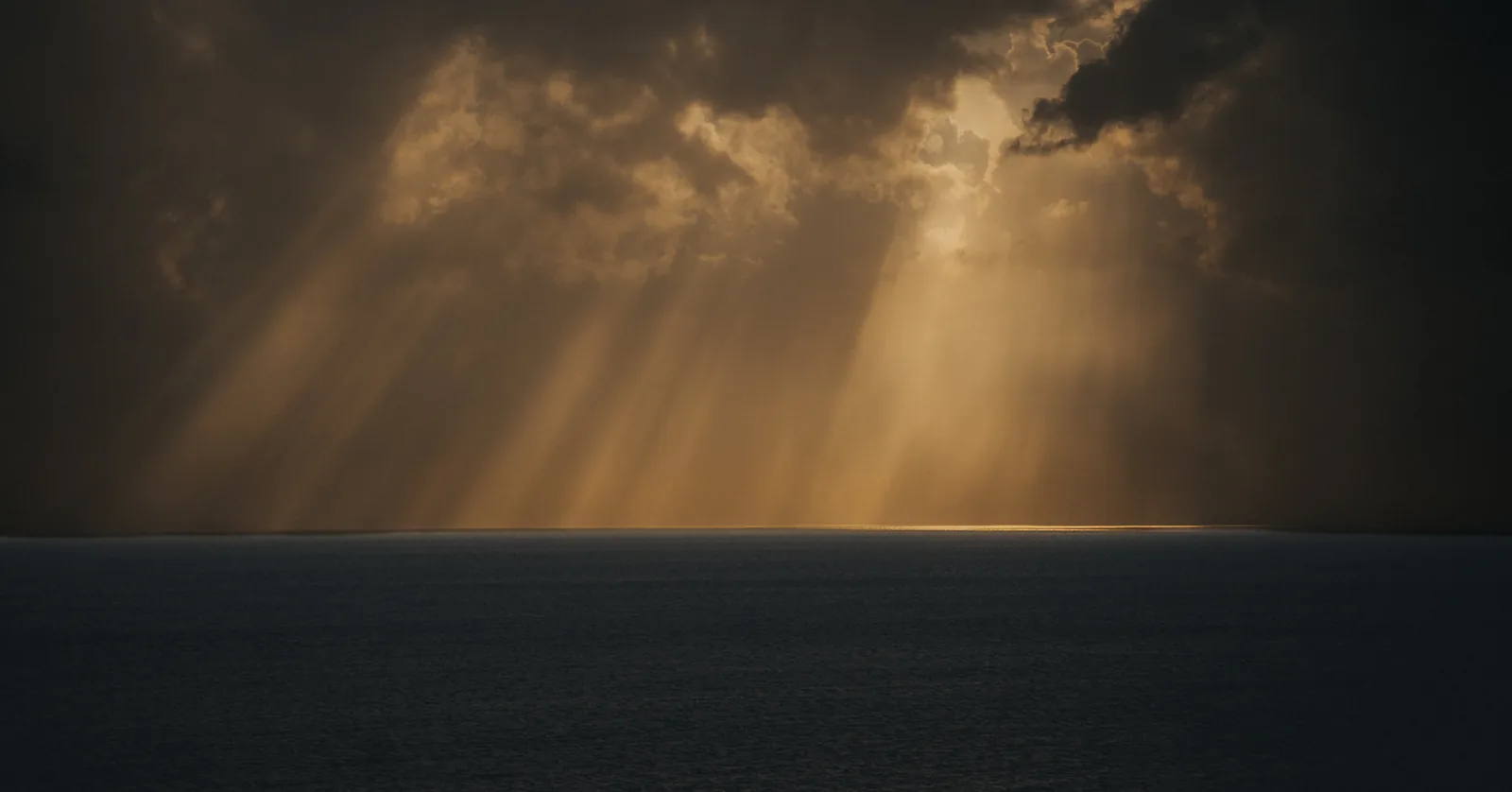 Dramatic sunbeams piercing storm clouds over open water in Sweden