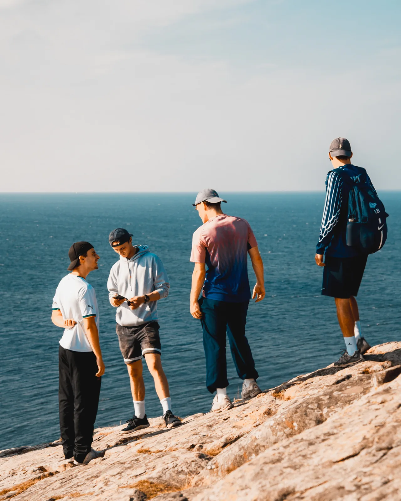 Friends standing on a rocky coastal ledge overlooking the open sea in Sweden