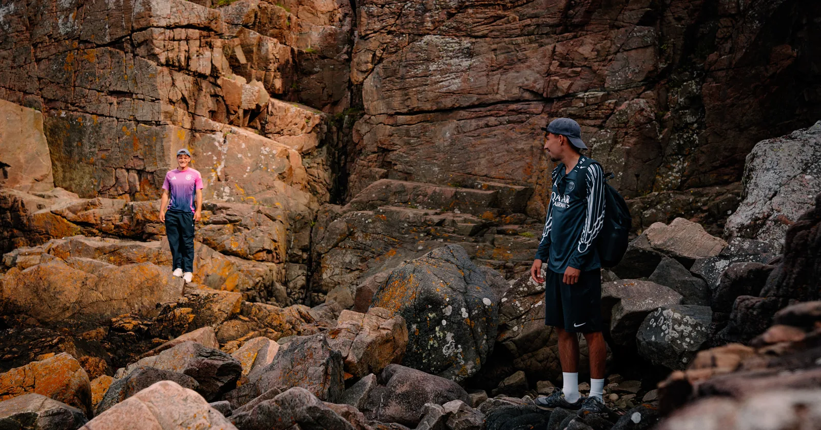 Friends picking their way across boulders in a rocky coastal gully in Sweden