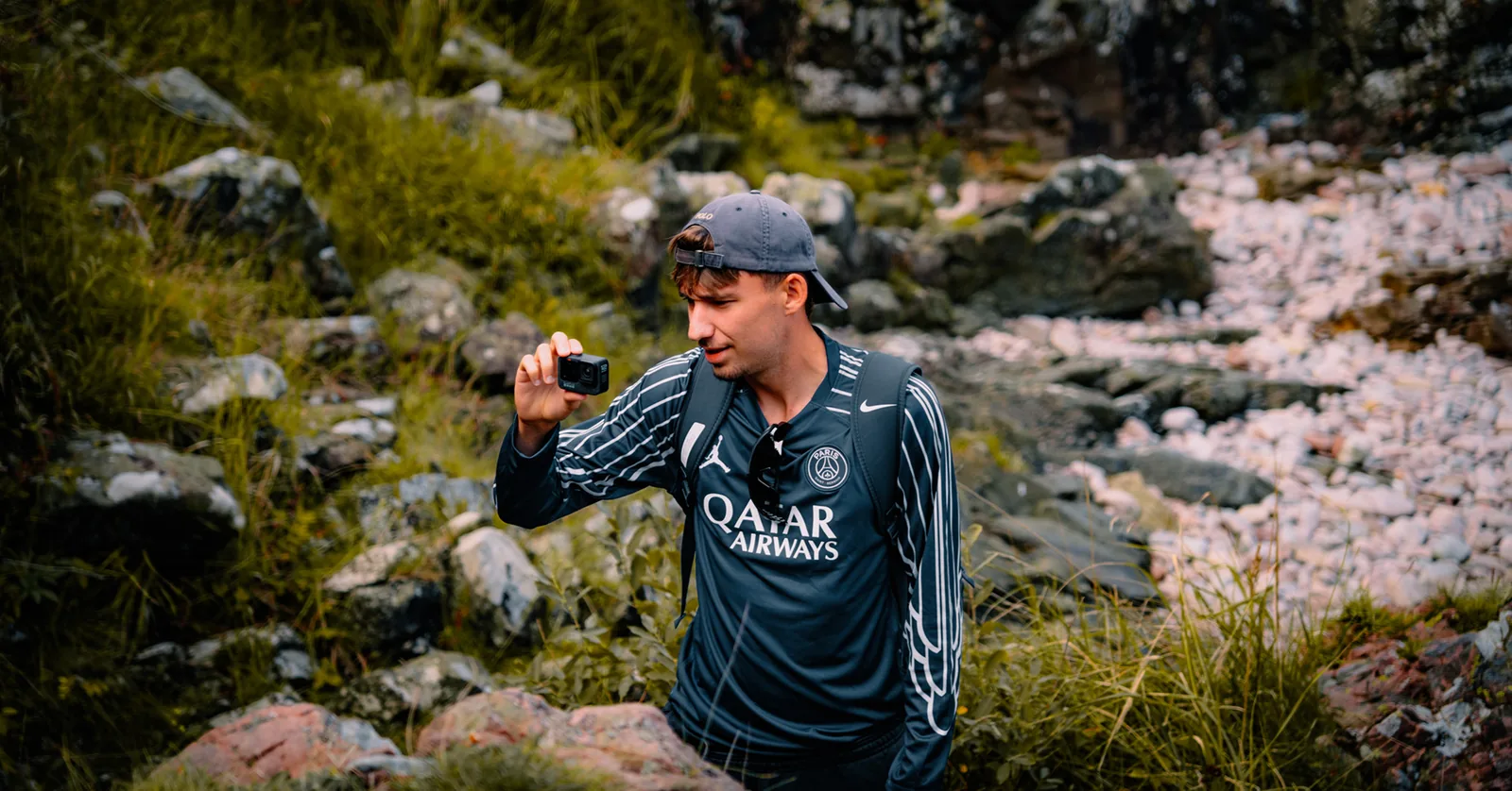 Man recording footage with a handheld camera in a mossy rocky ravine in Sweden