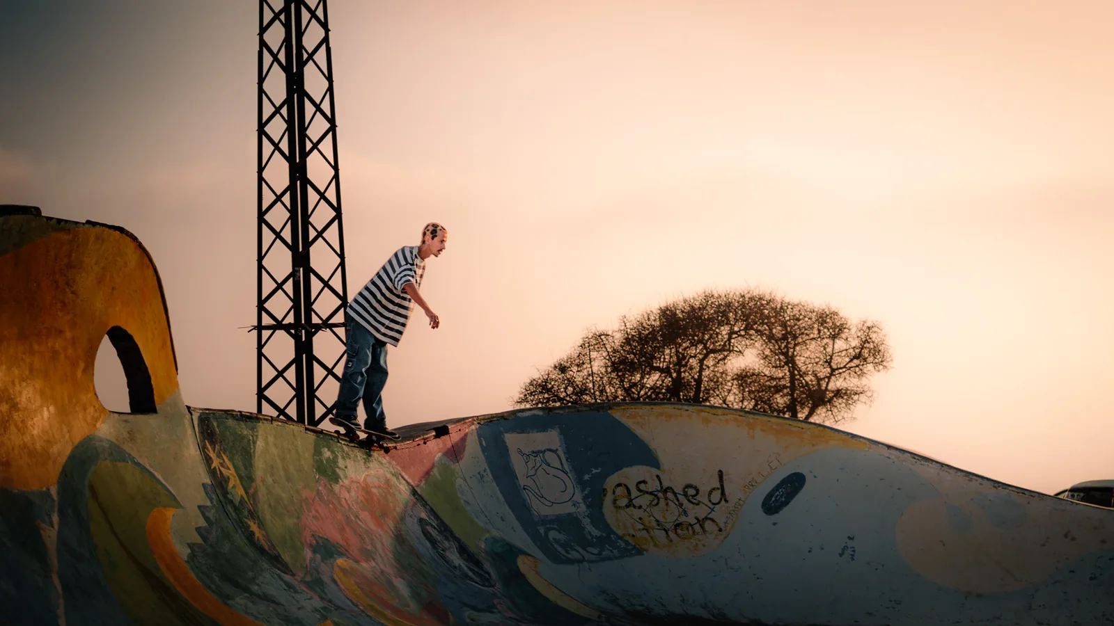 A skateboarder grinds along a painted ramp edge at dusk in Taghazout, Morocco