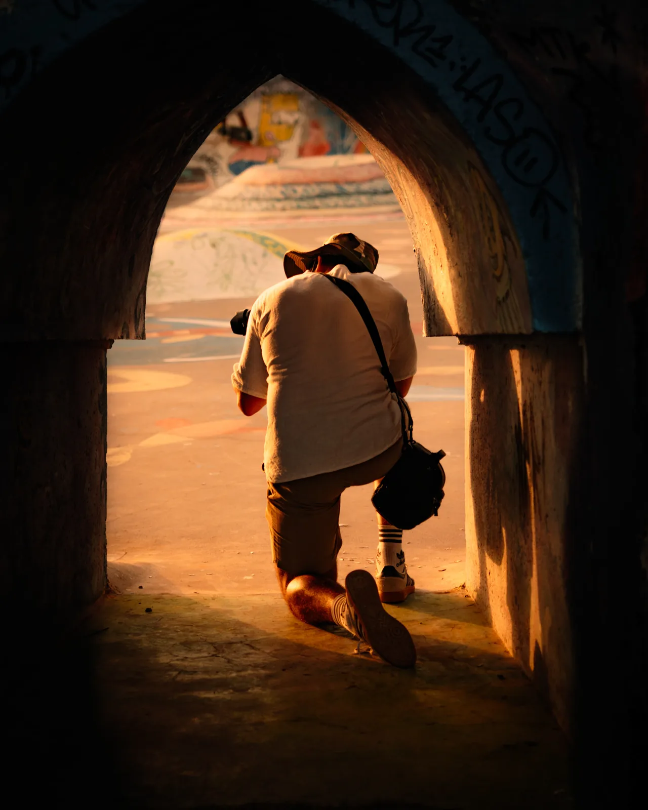 A photographer kneels beneath a stone archway to frame a shot in Taghazout, Morocco