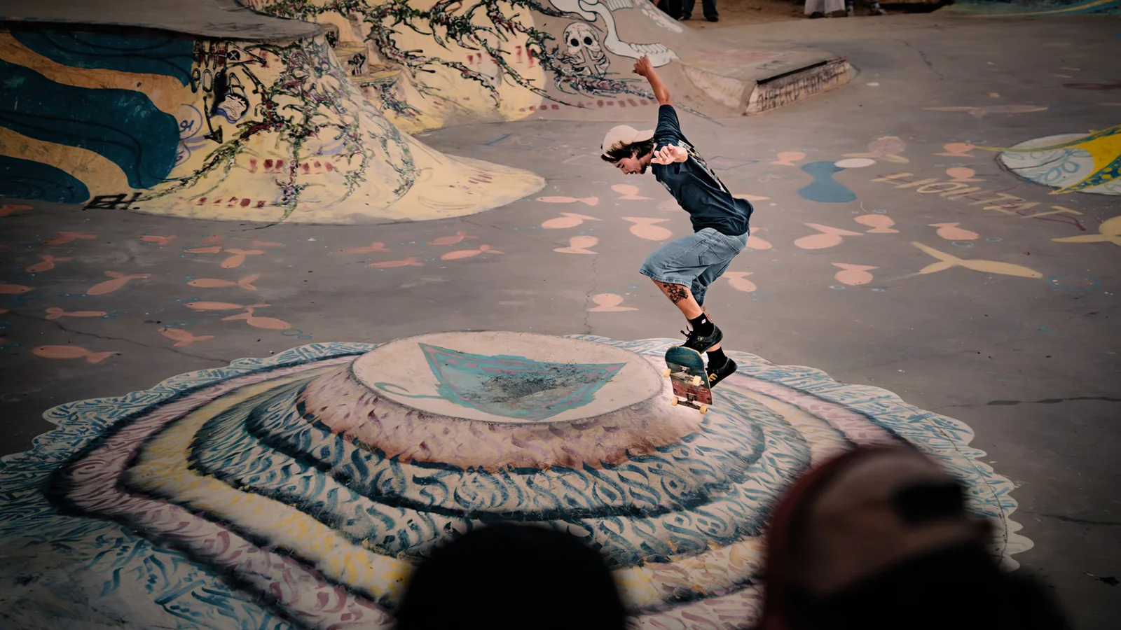 A skater launches into the air above a mural-painted bowl in Taghazout, Morocco