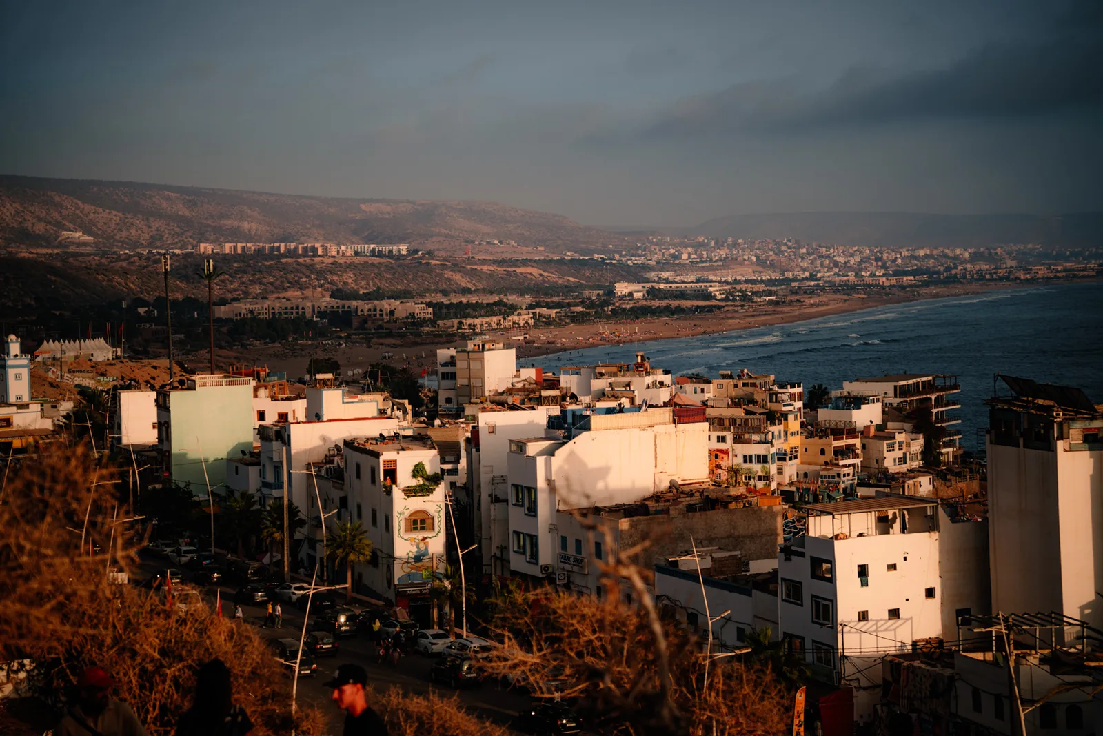 Whitewashed buildings cascade down a hillside above the coast at Taghazout, Morocco